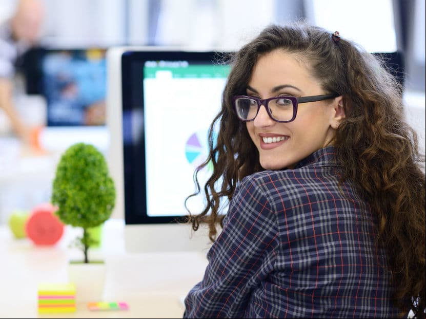Mujer jóven sonriendo frente a una computadora