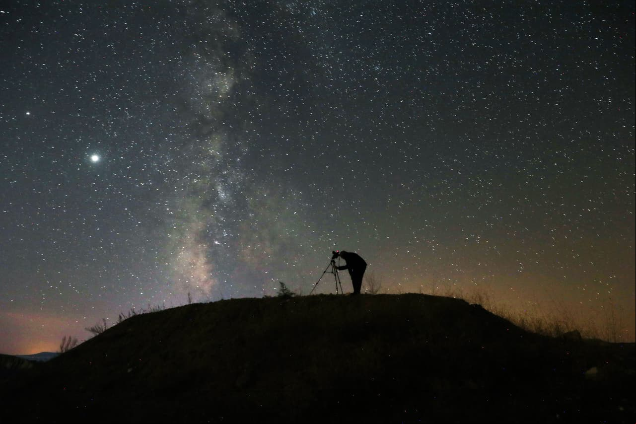 TOPSHOT - A person takes a photo with a camera on a tripod of the Milky Way at Nallihan district, in Ankara, on August 12, 2020. (Photo by Adem ALTAN / AFP) (Photo by ADEM ALTAN/AFP via Getty Images)